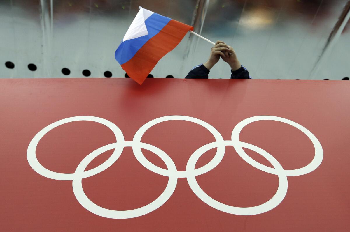 A fan holds the Russian flag over the Olympic rings during the 2014 Sochi Games.