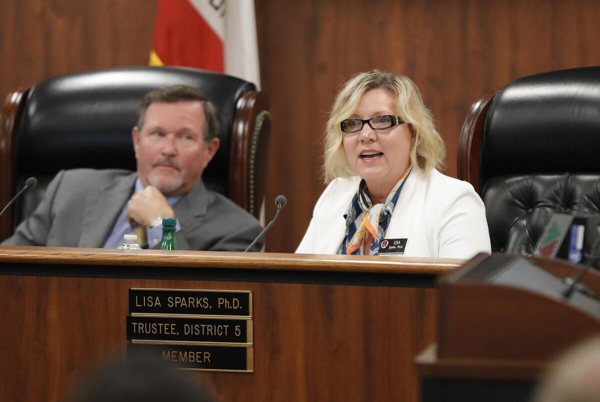 Ken Williams, left, listens as fellow Orange County Board Education trustee Lisa Sparks speaks during a meeting.