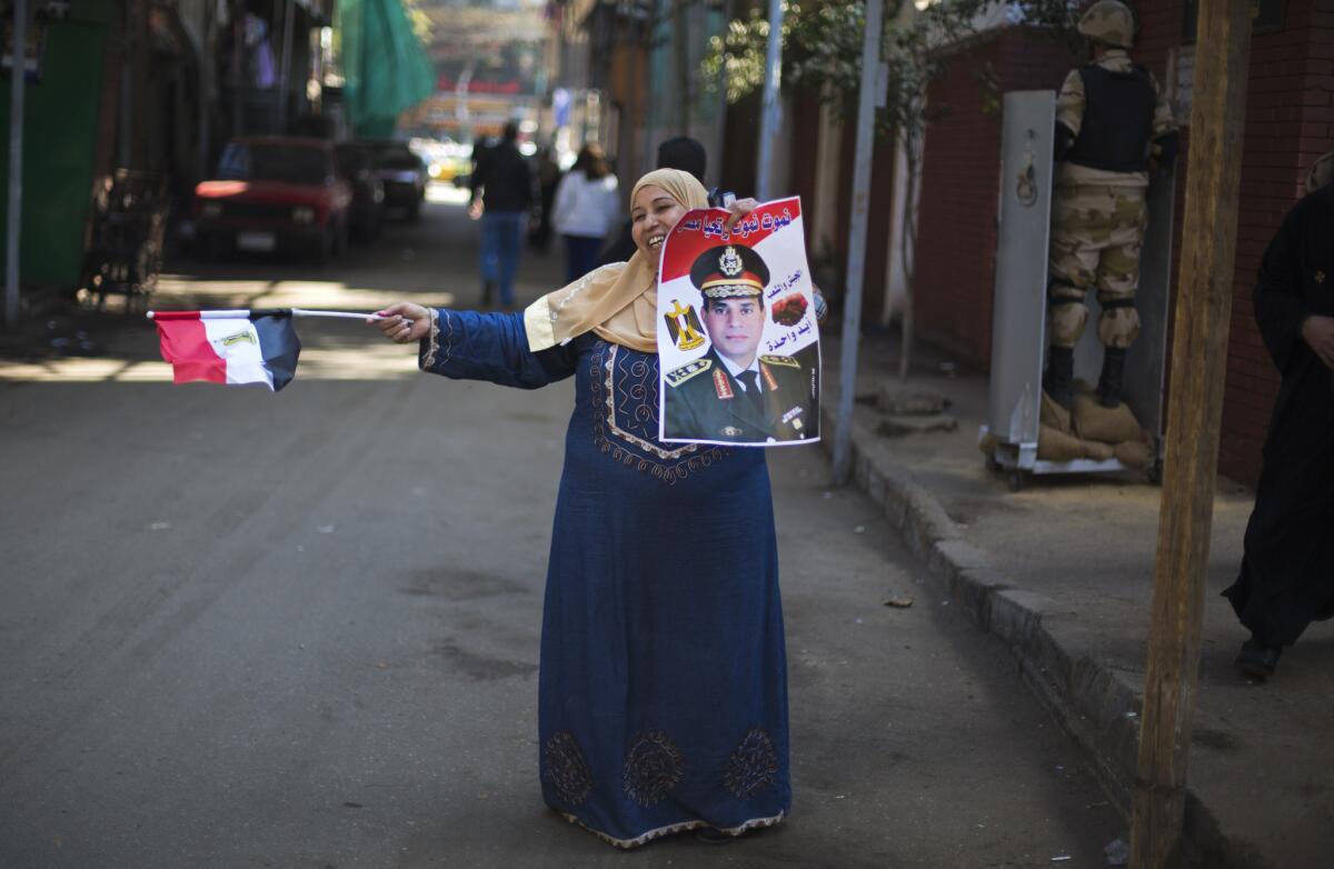 An Egyptian woman dances in front of a polling station on Wednesday while holding a poster of Egypt's defense minister, Gen. Abdel Fattah Sisi, and a national flag on the second day of voting in the country's constitutional referendum in Cairo.