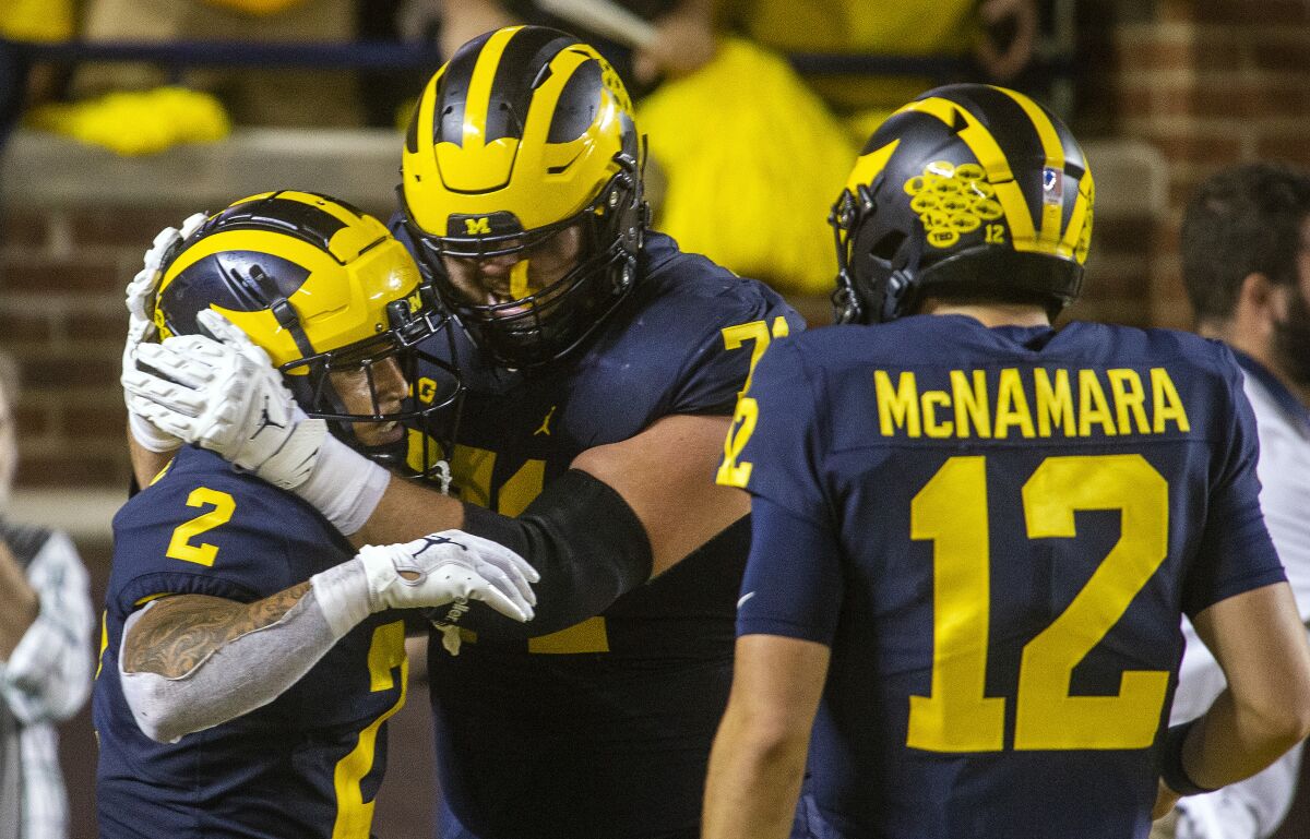 Michigan running back Blake Corum (2) celebrates his 67-yard touchdown with offensive lineman Andrew Stueber, center, and quarterback Cade McNamara (12) in the second quarter of an NCAA college football game against Washington in Ann Arbor, Mich., Saturday, Sept. 11, 2021. (AP Photo/Tony Ding)