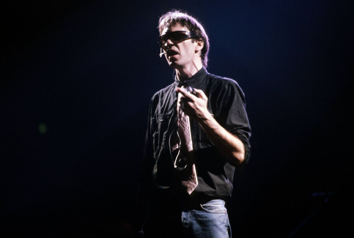 A man onstage in dark glasses