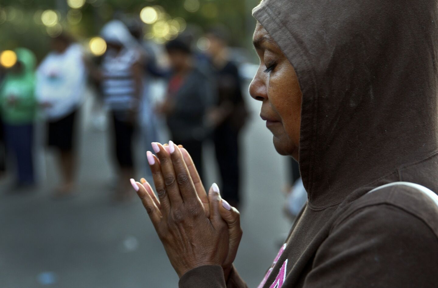 Alicia Dhanifu, wearing a hoodie in support of slain teenager Trayvon Martin, prays during a demonstration in Pasadena.