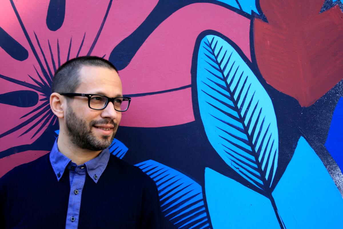 Lawrence Schimel in front of a bold mural of leaves