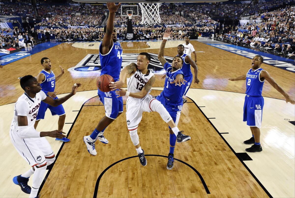 Connecticut guard Shabazz Napier passes around Kentucky's Dakari Johnson during the NCAA college basketball championship game.