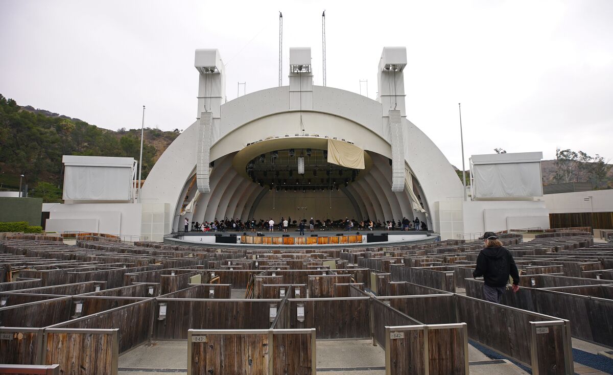 A person walks between the boxes near the shell of the Hollywood Bowl on an overcast day.