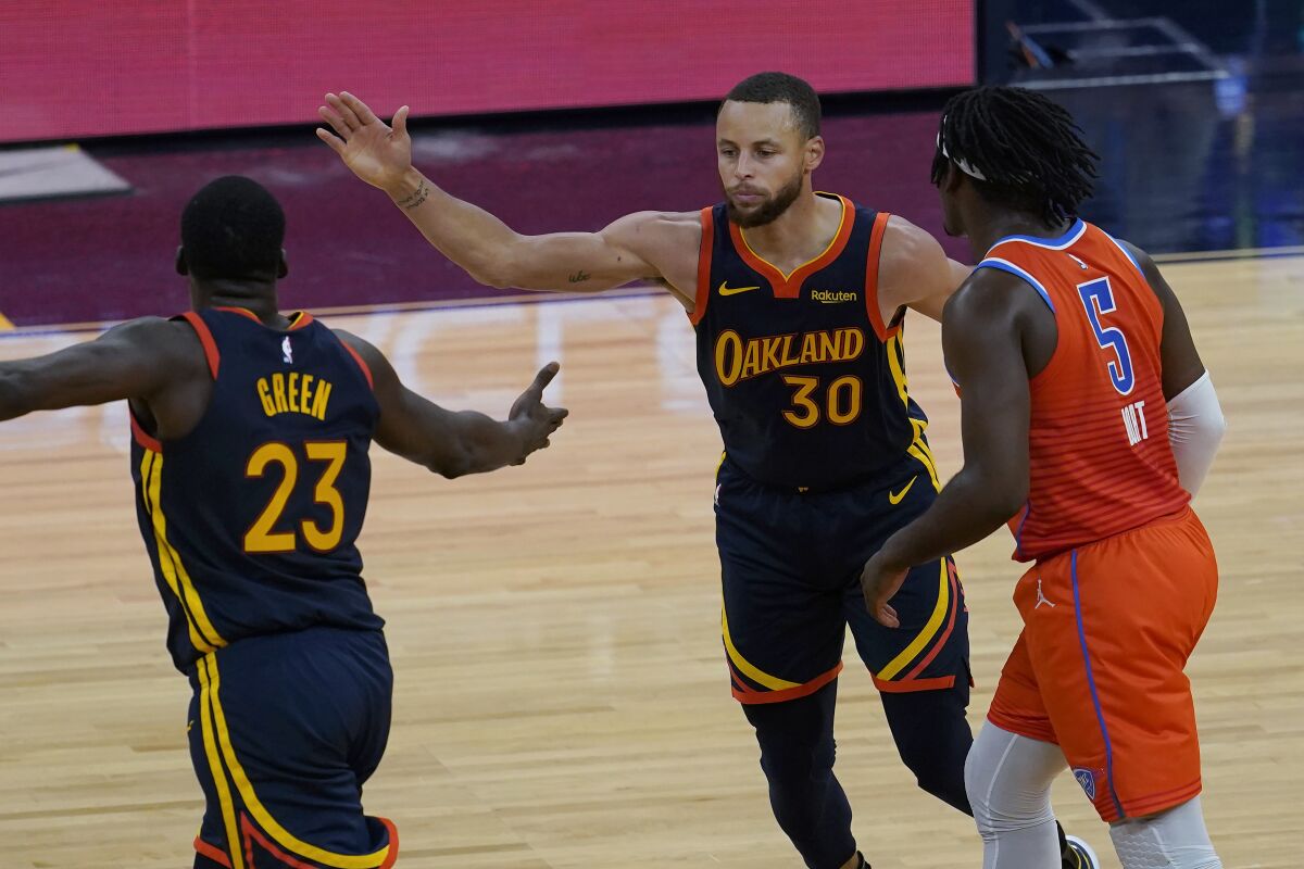 Golden State Warriors forward Draymond Green (23) and guard Stephen Curry (30) celebrate next to Oklahoma City Thunder forward Luguentz Dort (5) during the second half of an NBA basketball game in San Francisco, Thursday, May 6, 2021. (AP Photo/Jeff Chiu)