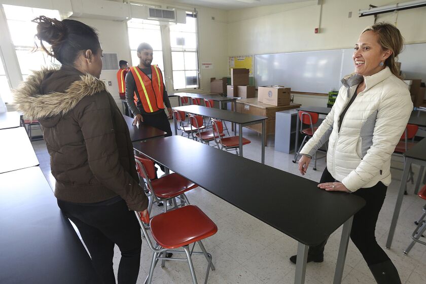 Porter Ranch Community School science teacher Rosie Van Zyl moves tables into position with the help of other LAUSD employees in her new classroom at Northridge Middle School.