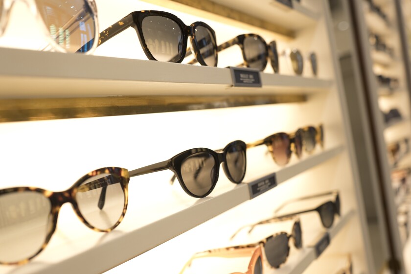 Eyeglasses sit on shelves at a store.