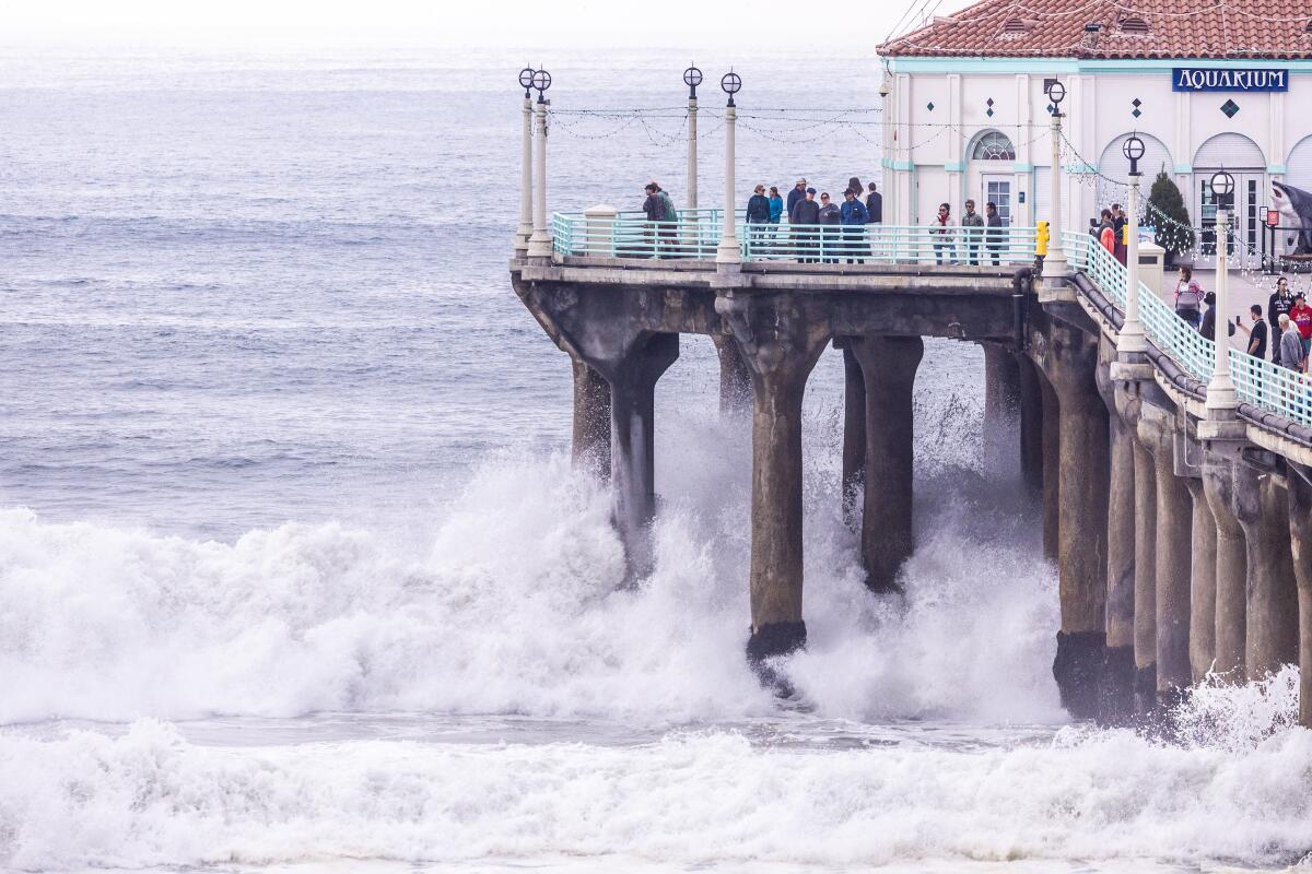 Visitors to Manhattan Beach Pier watch as waves crash under the pier during a high surf event.