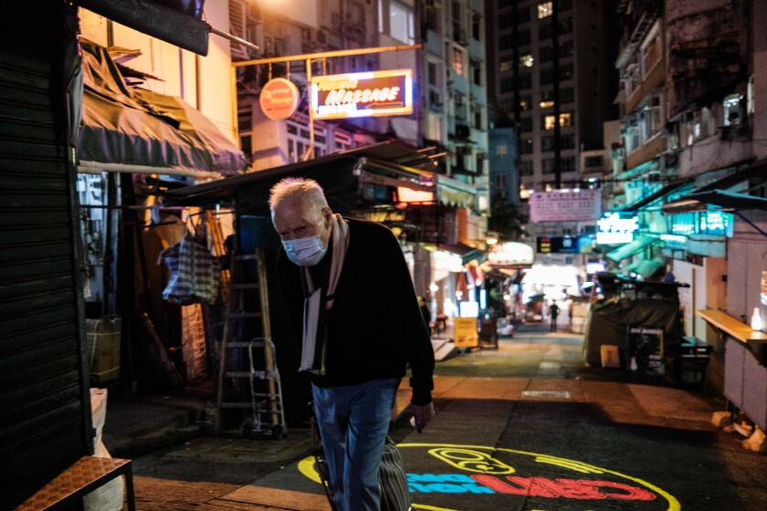 A man wears a face mask as he walks along a street popular for its restaurants and bars in Hong Kong after the city's chief executive announced plans to temporarily ban the sale of alcohol to help stop the spread of the coronavirus.
