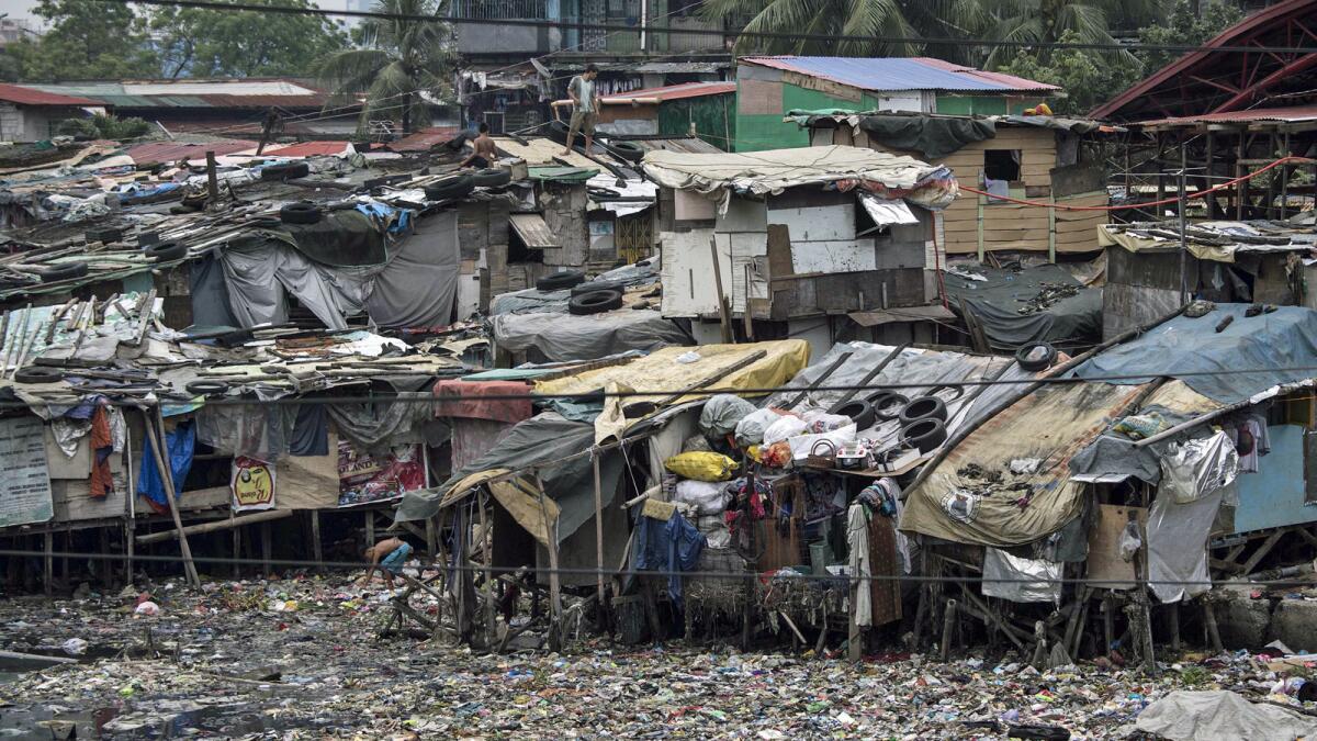 Residents of a Manila slum place tires on top of their homes to secure the roofs.