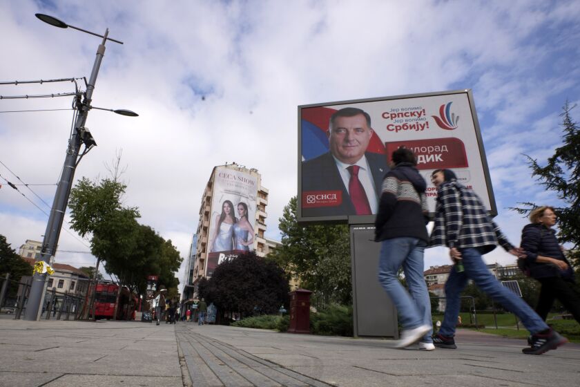 People walk past a pre-election billboard showing Bosnian Serb leader Milorad Dodik in Belgrade, Serbia, Thursday, Sept. 22, 2022. Bosnia has a general election on Oct. 2, in which Dodik is running for the Bosnian Serb presidency. (AP Photo/Darko Vojinovic)