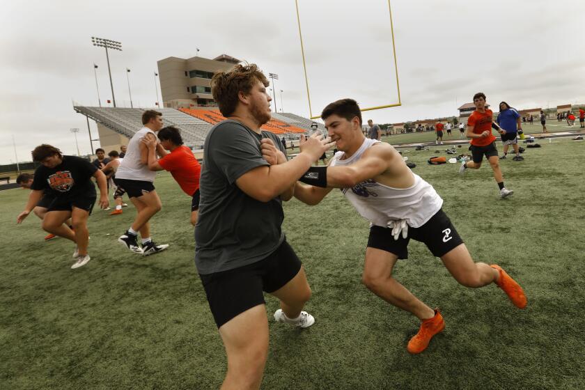 ALEDO, TEXAS-July 28, 2020-At Aledo High School in Aledo, Texas, football players practice after having their temperatures checked. Coach Tim Buchanan, of Aledo High School football team, says said. "It's important to our kids, it's important to our communities and to the state of Texas. I honestly think our kids are safer at school and when they're at practice because we're going to make them social distance and follow the guidelines." (Carolyn Cole/Los Angeles Times)