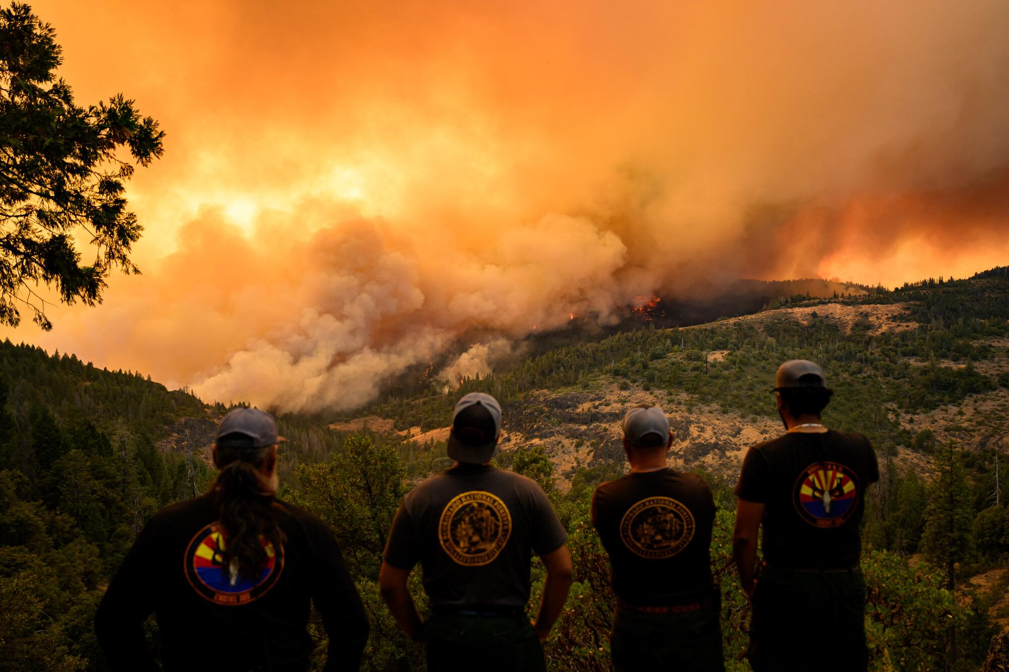Firefighters watch as flames and smoke move through a valley in the Forest Ranch area of Butte County.