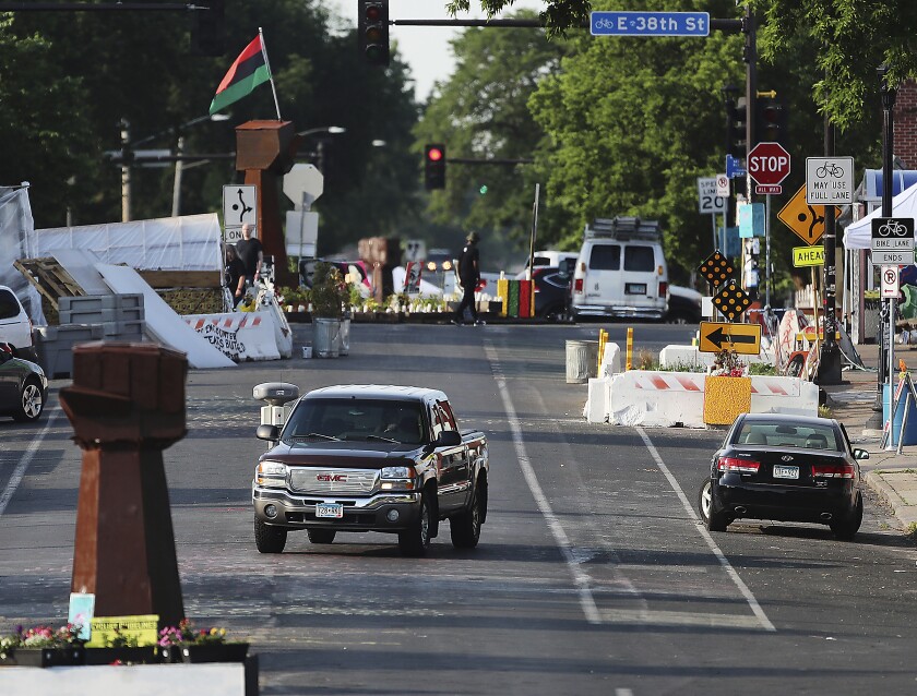 A vehicle travels along Chicago Ave. S. Near E. 38th St. at George Floyd Square, Tuesday, June 8, 2021, in Minneapolis, after city crews returned to GFS to remove debris and barriers for the second time in an attempt to open the intersection to traffic. (David Joles/Star Tribune via AP)