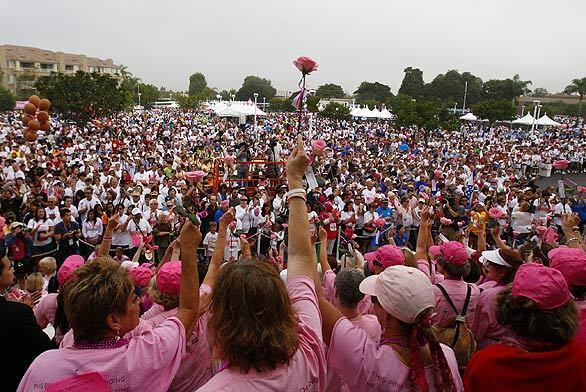 Gay Royer, center, of Costa Mesa, a five-year cancer survivor, hoists a rose into the air as she listens to fellow survivors at this year's Susan G. Komen Orange County Race for the Cure at Fashion Island in Newport Beach. An estimated 30,000 breast cancer survivors, supporters and activists took part.