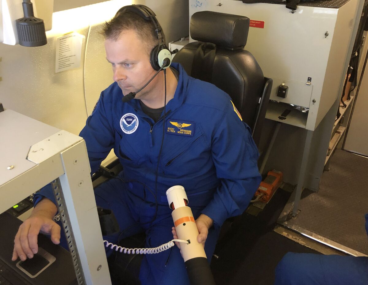A man prepares to deploy a dropsonde from a jet over an atmospheric river. 