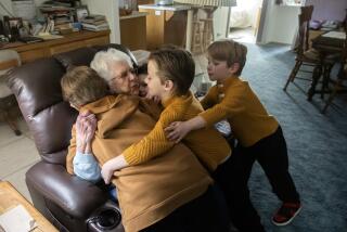 WRIGHTWOOD, CA - DECEMBER 27: The Zamora children Jax, 9, left; Mason, 7, (rear); Evan, 7, and Drew, 7, give a goodbye hug to neighbor Eva Jablonsky following a visit. Jax helps her with her internet setup. She enjoys having them over saying she likes it when her house is full. Wrightwood Elementary School's "Golden Raccoon" program has families "adopting" senior citizens in the community. The name of the program was created by the principal of the school whose mascot is a raccoon. Photographed in Wrightwood, CA on Wednesday, Dec. 27, 2023. (Myung J. Chun / Los Angeles Times)
