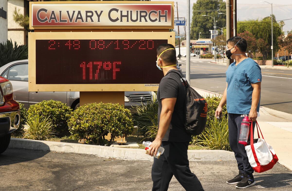 Pedestrians walk past a church's temperature display during a record-breaking heat wave in Woodland Hills on Aug. 19, 2020. 