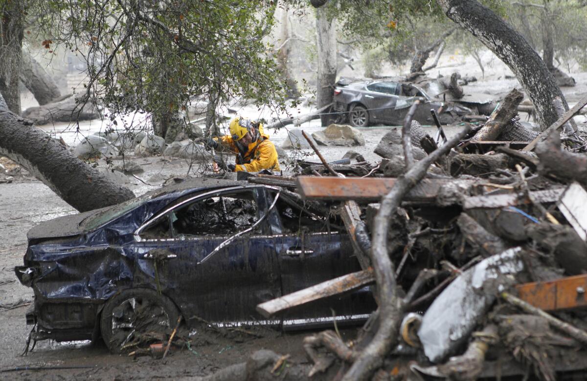 A member of the Long Beach Search and Rescue team looks for survivors in a car in Montecito, Calif. on Tuesday, Jan. 9, 2018.