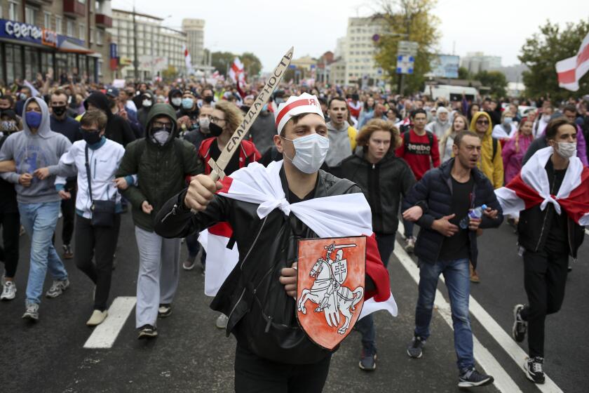 Demonstrators, one of them wearing an old Belarusian nation flag and holding a cardboard sword reading "solidarity" march during an opposition rally to protest the official presidential election results in Minsk, Belarus, Sunday, Sept. 27, 2020. Hundreds of thousands of Belarusians have been protesting daily since the Aug. 9 presidential election. (AP Photo/TUT.by)