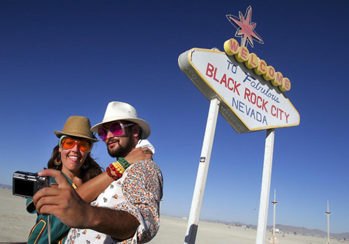 Simone Oliver of San Diego and Eric Weisz of San Francisco take a picture in front of a welcome to Black Rock City sign. Burning Man 2008 kicked into full gear as participants from around the world begin to arrive in Nevada for the annual art event that culminates with the burning of a large art installation over the weekend. More photos >>>