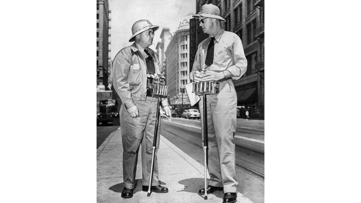 June 15, 1953: Daniel G. Hunsaker, left, and Red Sorensen were among downtown traffic loaders for Los Angeles Transit Lines who made change into summer uniforms, complete with sun helmets.