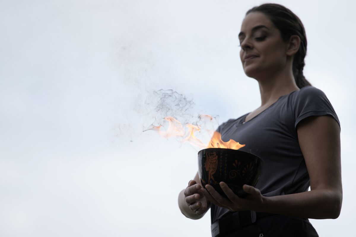 Greek actress Xanthi Georgiou, playing the role of the High Priestess, carries the flame during the final rehearsal for the lighting of the Olympic flame at Ancient Olympia site, birthplace of the ancient Olympics in southwestern Greece, Sunday, Oct. 17, 2021. The flame will be transported by torch relay to Beijing, China, which will host the Feb. 4-20, 2022 Winter Olympics. (AP Photo/Petros Giannakouris)