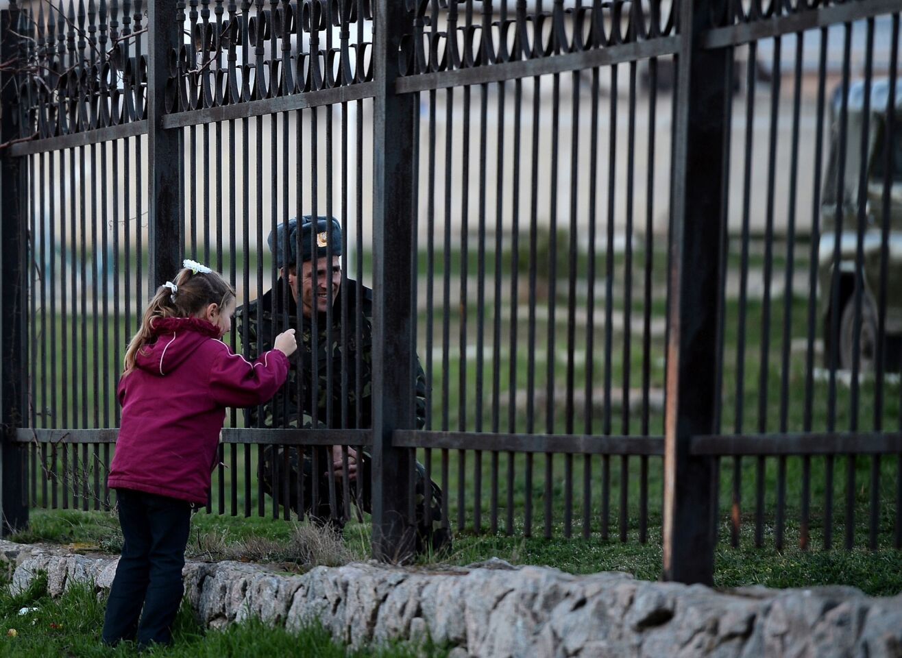 A Ukrainian soldier speaks to his daughter through a gate as he waits inside the Sevastopol tactical military brigade base near Belbek in Sevastopol.
