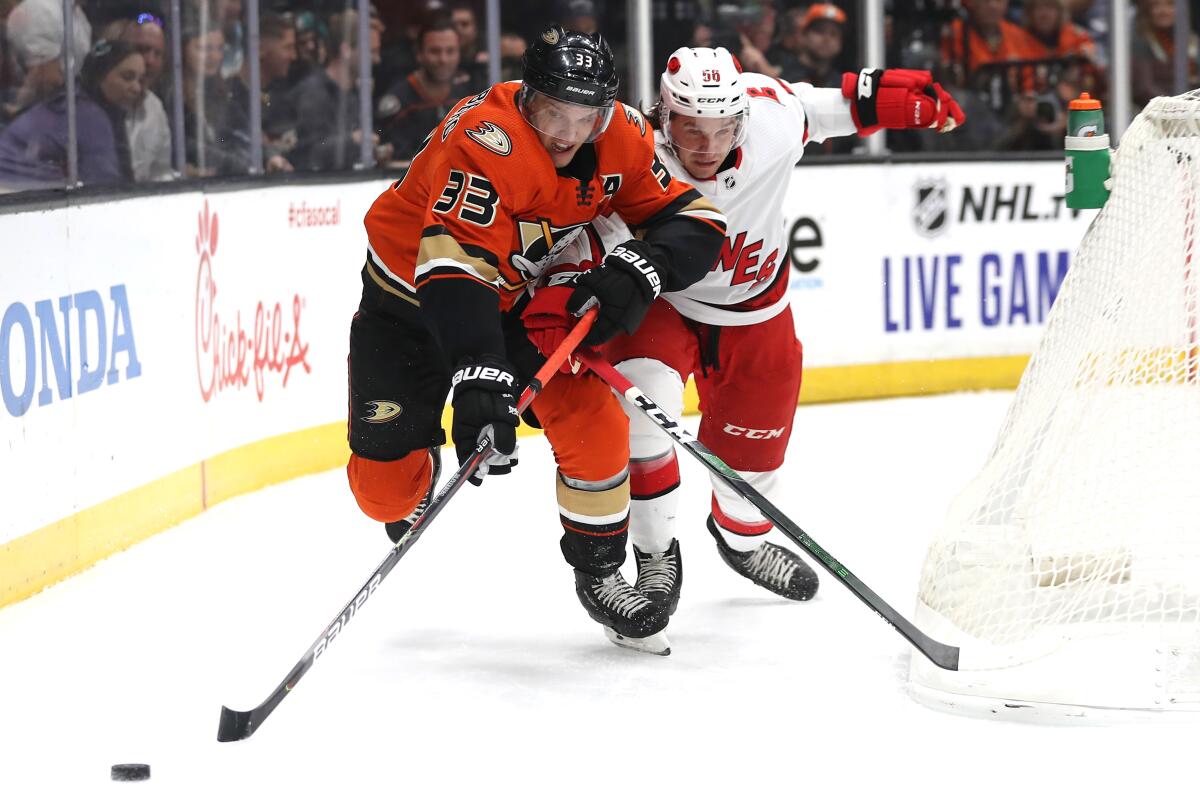 The Ducks' Jakob Silfverberg battles the Hurricanes' Erik Haula for a loose puck during the first period at Honda Center on Oct. 18.