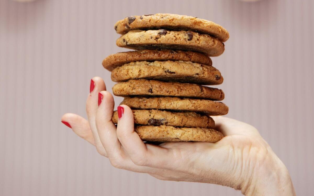 A manicured hand holds a stack of Vegan Gluten-Free Chocolate Chip Cookies.