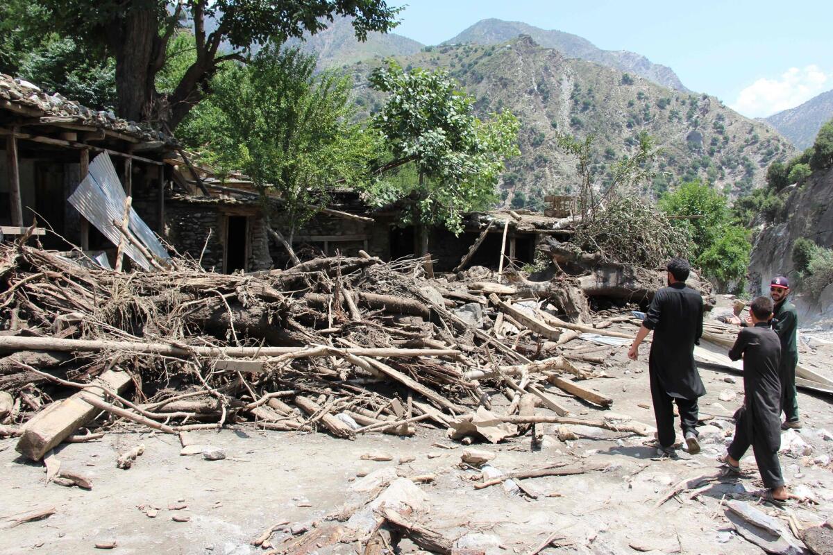 People gather around damaged houses in the Pakistani village of Ursoon on Sunday.