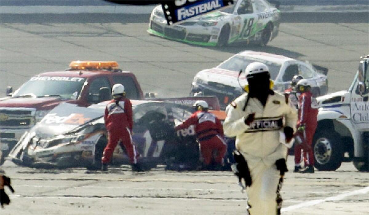 Denny Hamlin's wrecked car is tended to by rescue workers after colliding with Joey Logano during the final lap of the NASCAR Sprint Cup series race at Fontana last year.