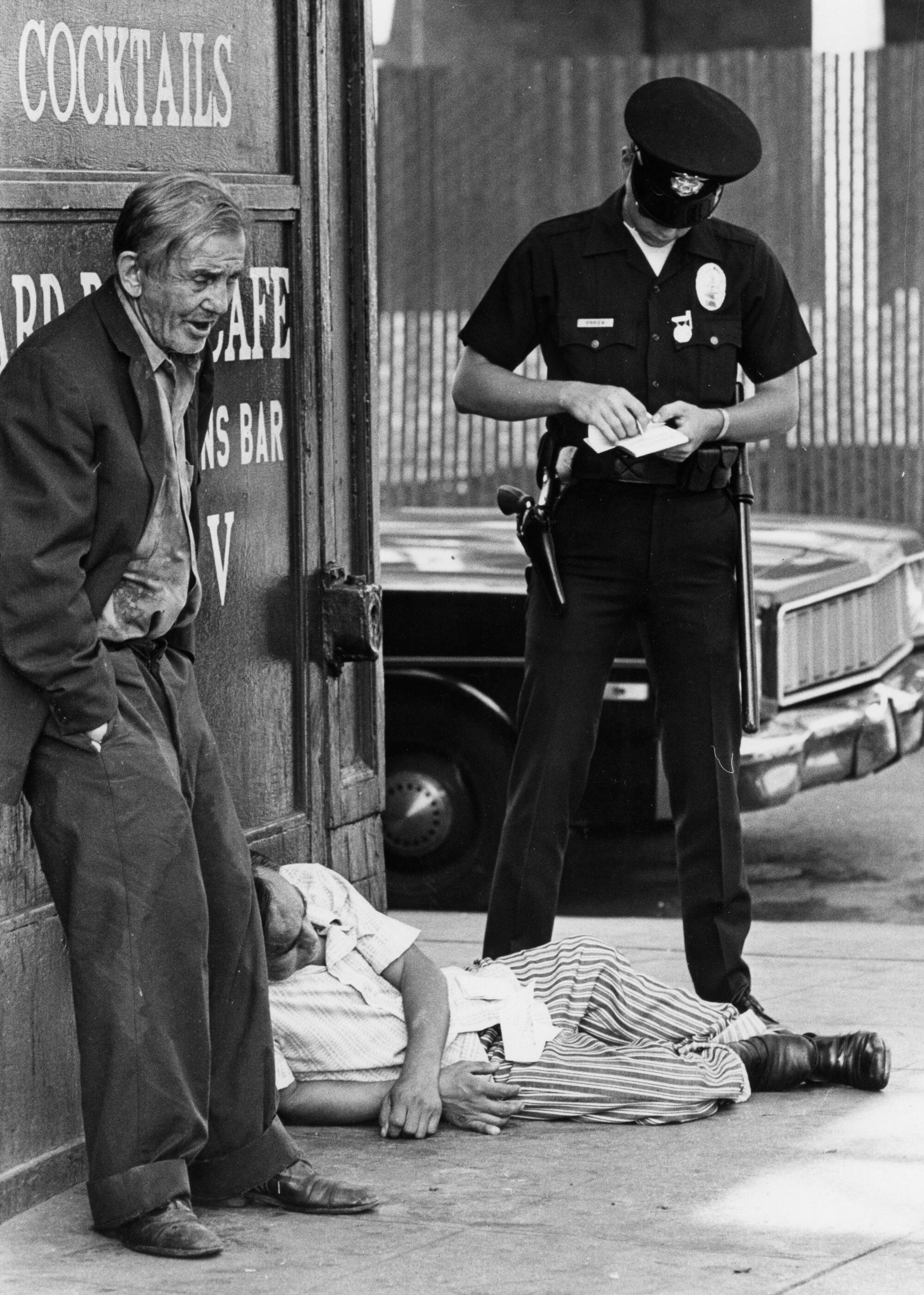 A police officer watches two men on the street.