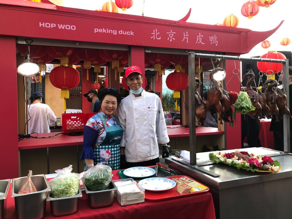 A family photograph of Judy and Yening “Lupe” Liang of Hop Woo restaurant serving Peking duck at an outdoor event.
