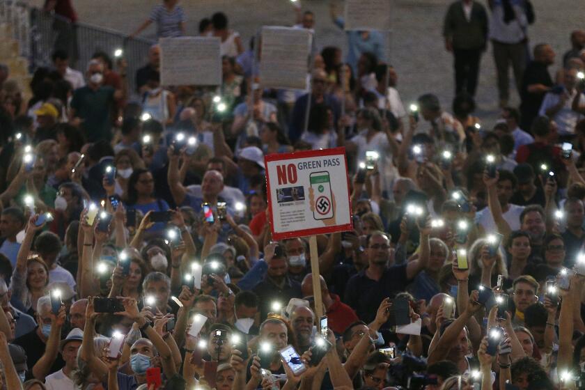 FILE - In this Wednesday, July 28, 2021 file photo, people stage a protest against the COVID-19 vaccination pass in Rome. Shouts of “liberty” have echoed through Italian and French streets and squares as thousands show their opposition to plans to require vaccination cards to continue normal social activities, like dining indoors at restaurants, visiting museums or cheering home teams in stadiums. (Cecilia Fabiano/LaPresse via AP)