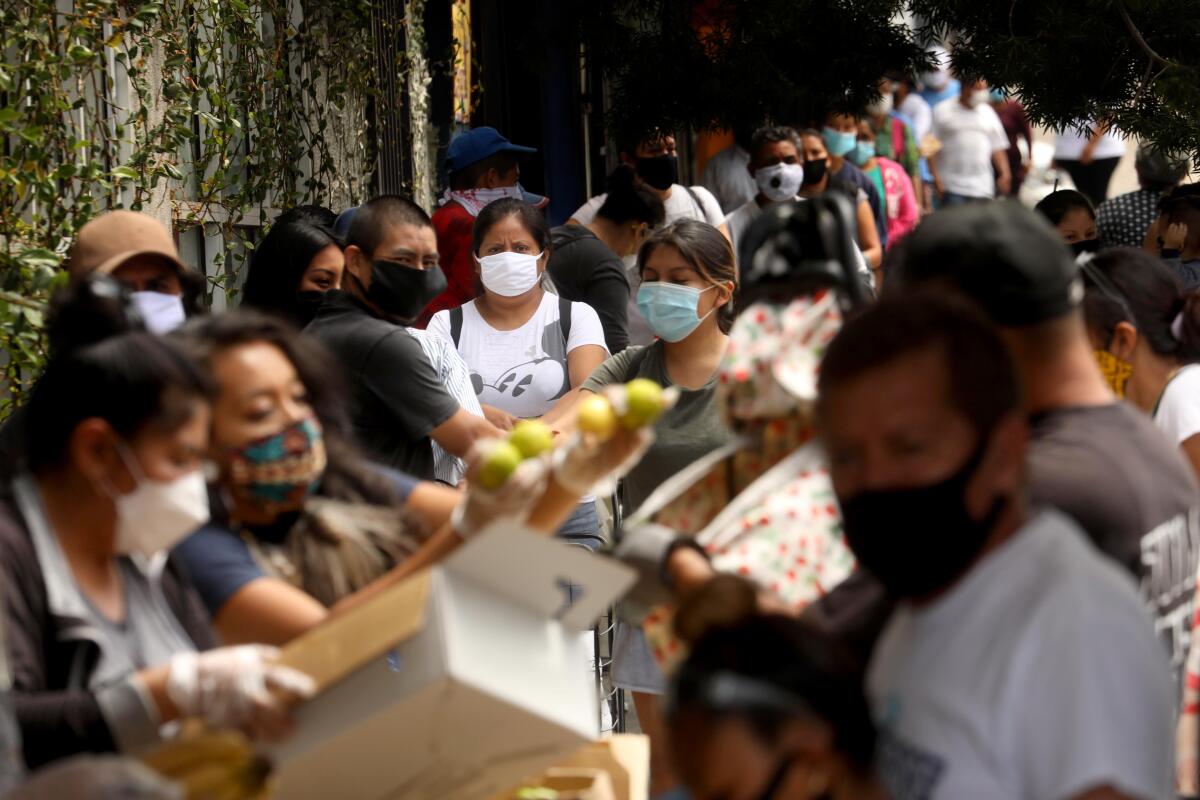 People struggling amid the pandemic wait in line in Koreatown on Wednesday to receive bags of food prepared by Homies Unidos.