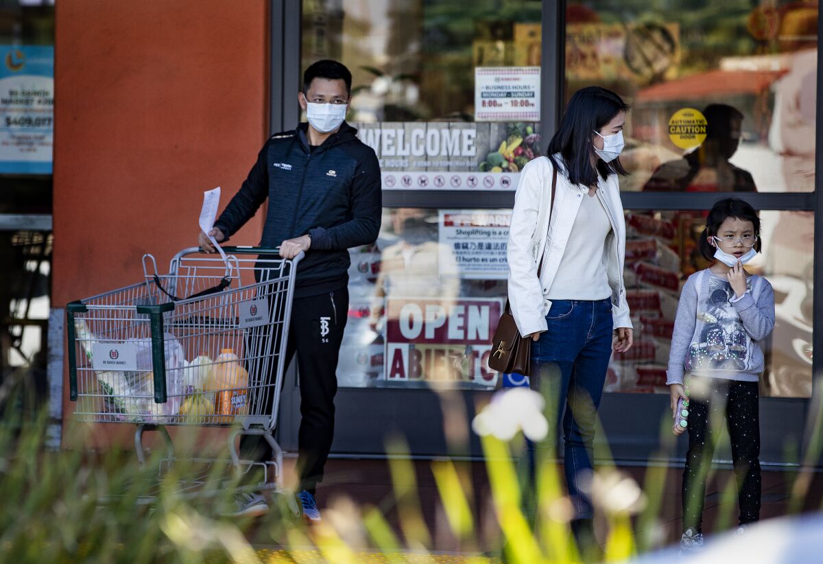 Sarah Chong, middle, who is visiting from Shanghai, and her family wear masks while shopping in San Gabriel on Jan. 29. She and her family are visiting the U.S. for a month.