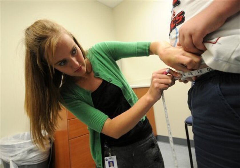 Ashley Potter, at left, an Exercise Physiologist with the H.E.A.R.T. Champions program at St. Mary's Medical Center in Huntington, W.Va., uses a tape to measure around the waistline of program participant Noah Retcher, 9, of Milton on Sept. 29, 2008. Those selected to participate in H.E.A.R.T. (Helping Educators Attack Risk Factors Together) Champions take part in regular exercise, cholesterol and blood pressure screening, and nutrition education. (AP Photo/Howie McCormick)