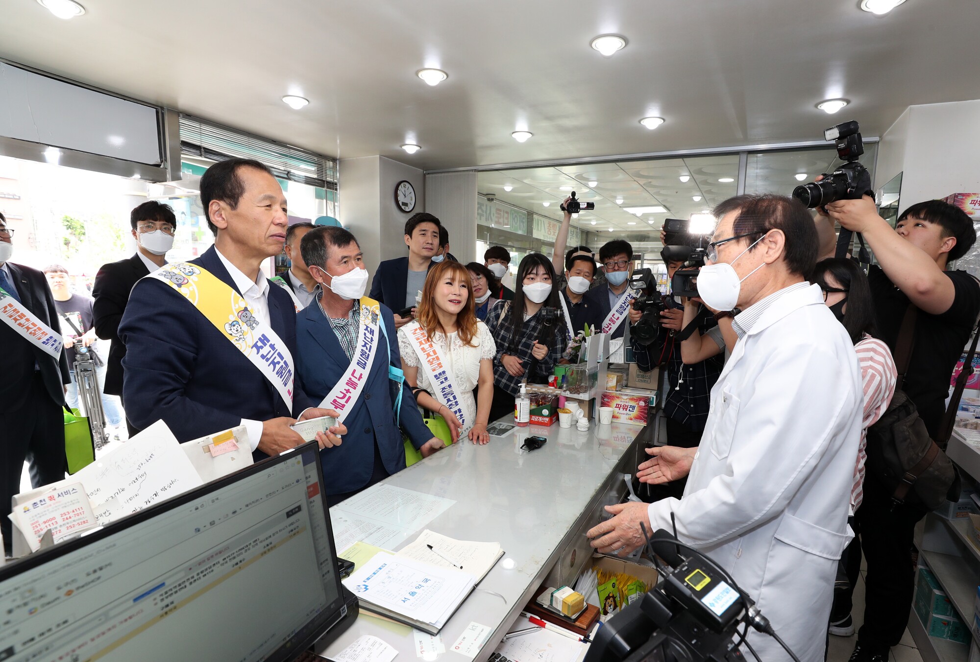 Gov. Choi Moon-soon, left, spends his stimulus money at the pharmacy of Lee Jong-ho, right.