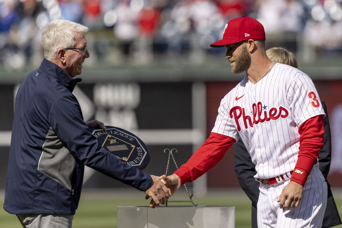 Philadelphia Phillies right fielder Bryce Harper (3) receives the MVP plaque from former Phillie Mike Schmidt before the start a baseball game against the Oakland Athletics, Saturday, April 9, 2022, in Philadelphia. (AP Photo/Laurence Kesterson)