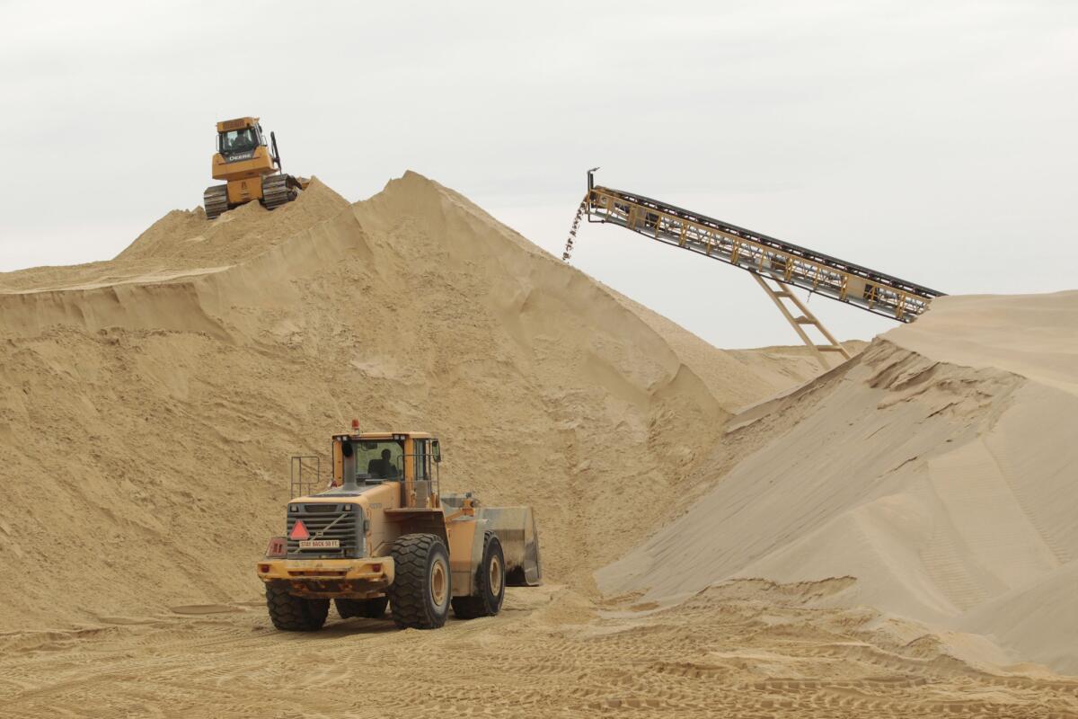 Front-end loaders work in 2012 around a mountain of stockpiled sand waiting to be screened for quality at a mine in Wisconsin.