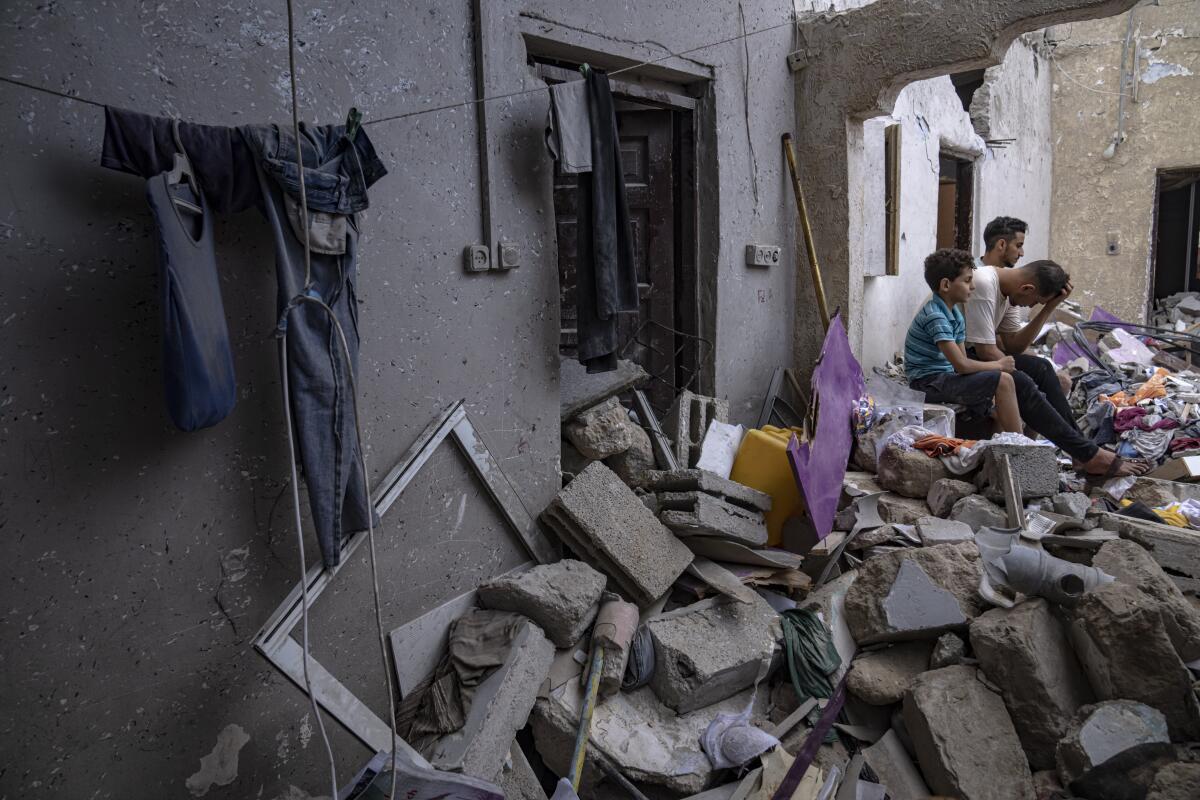 Palestinos sentados entre los escombros de una casa después de que fuera alcanzada por un bombardeo 