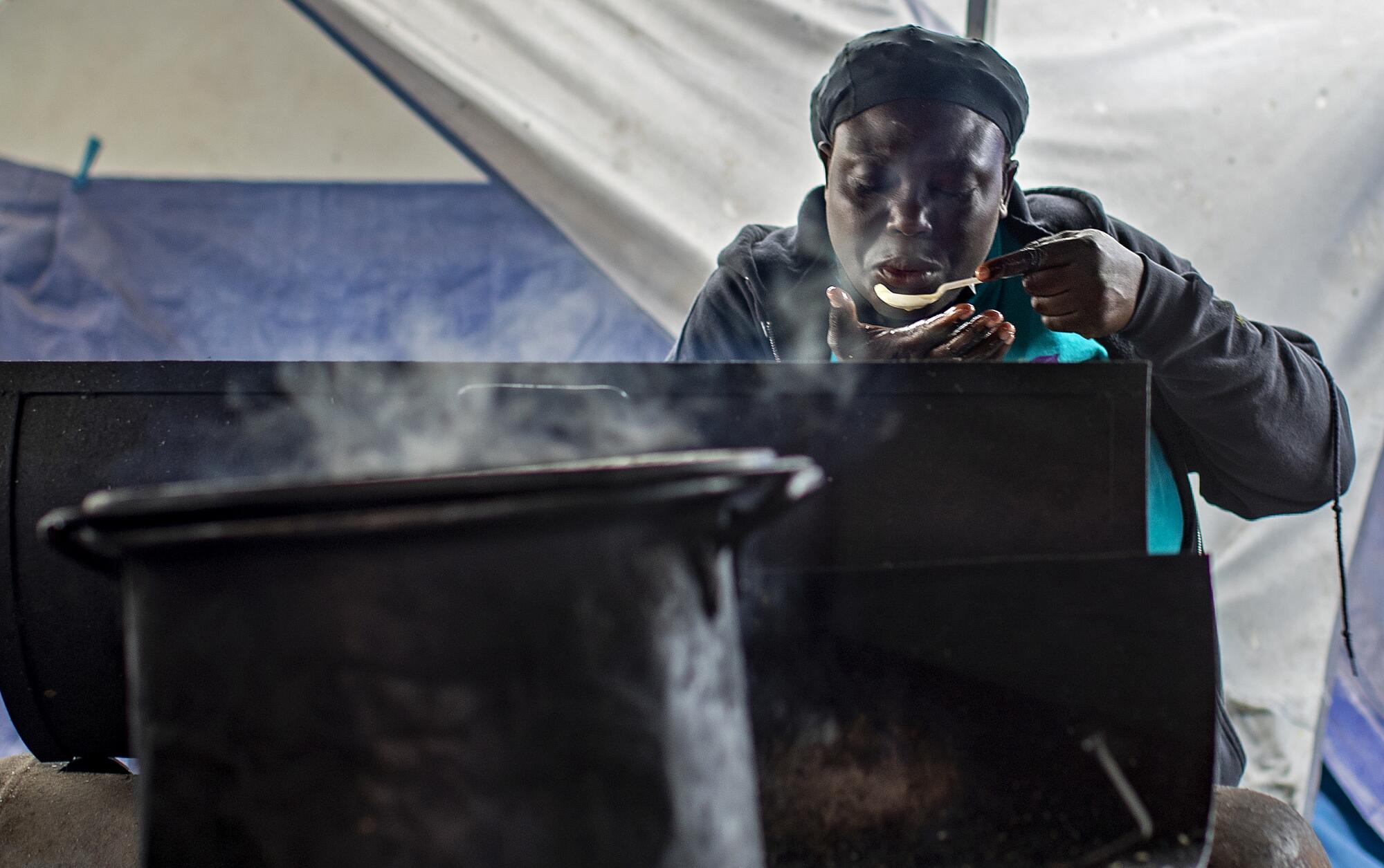 Claudia Chery tastes the stew she's making