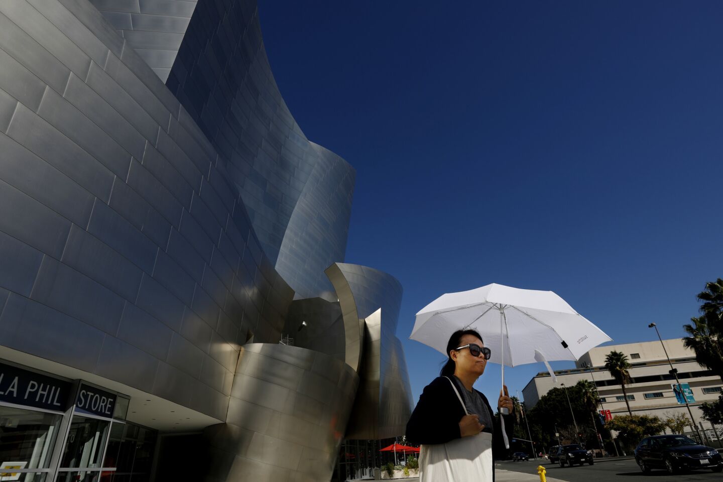 A pedestrian walking by Disney Concert Hall in downtown Los Angeles uses an umbrella for shade during the October heat wave.