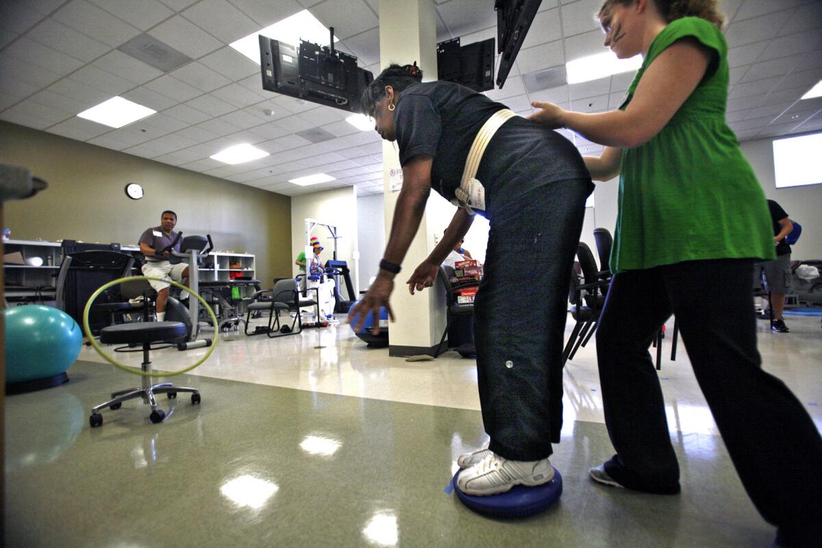 Chapman University student Cindy Mack, right, helps Janet Johnson keep her balance during boot camp. "You feel triumphant when you come here. You feel you made it. You're thriving," says Johnson, who since her 2009 stroke has worked on NASA projects.