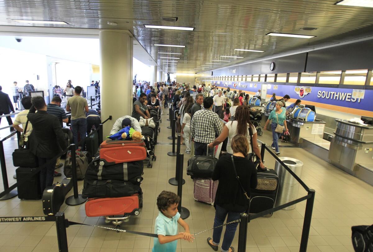 Travelers line up at the Southwest Airlines ticketing counter at Los Angeles International Airport. U.S. carriers reported a record high rate of seats filled and total international travelers in 2014, according to federal statistics.