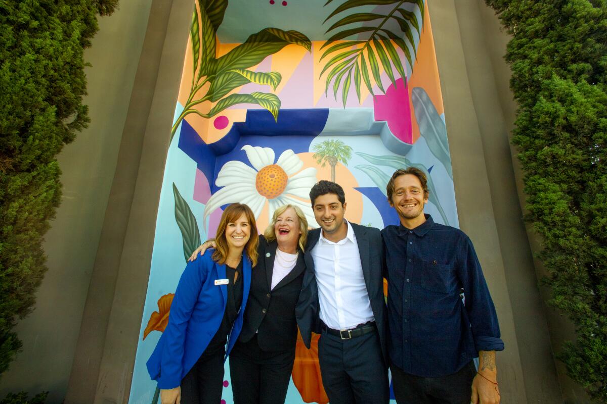 From left, Travel Costa Mesa President Paulette Lombardi-Fries, Mayor Katrina Foley, Triangle Square representative Tyler Mateen and artist Aaron Glasson celebrate the dedication of Glasson's "Costa Mesa Bloom" mural Wednesday.