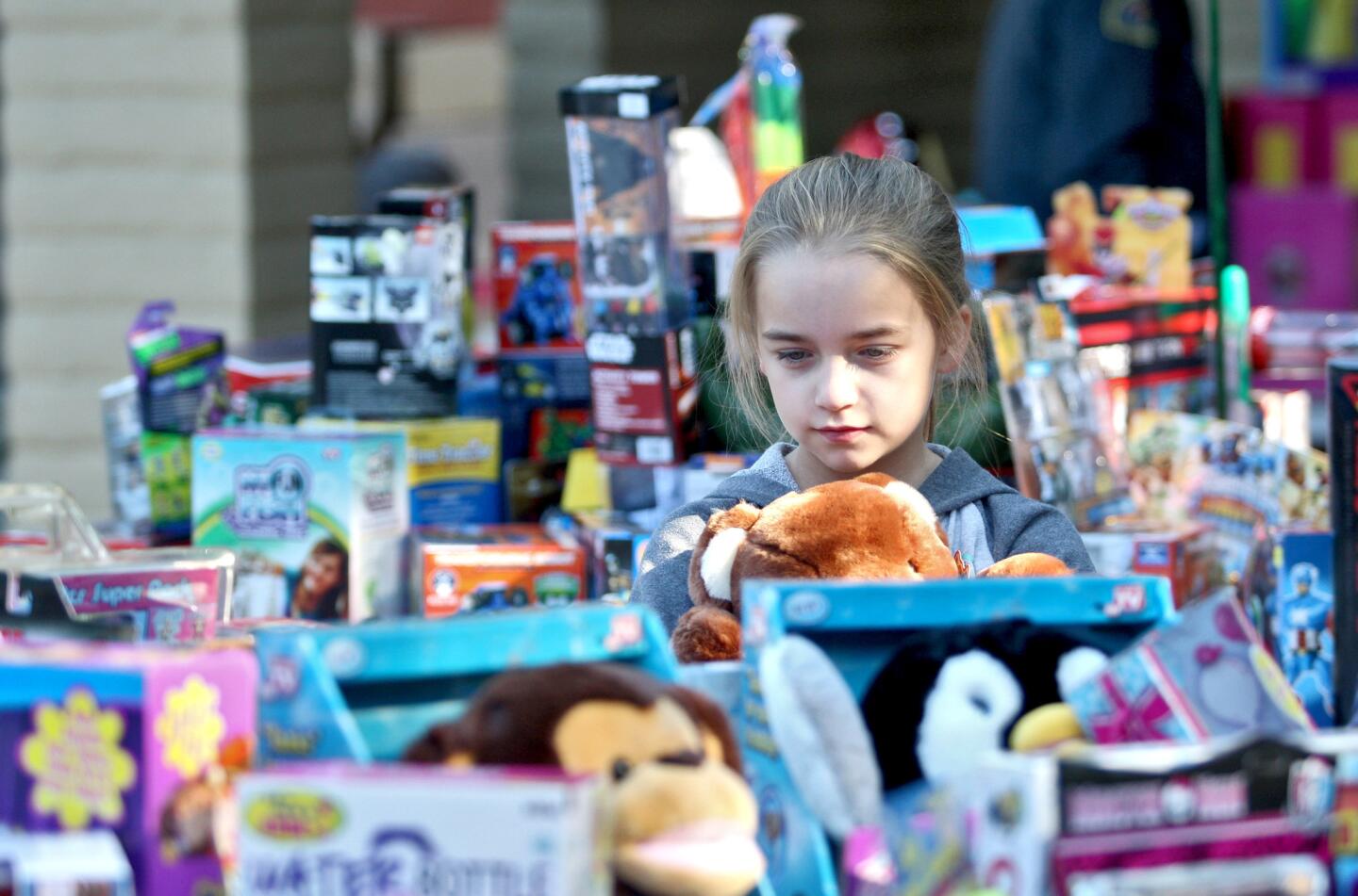 Ashley Fostrey, 9 of Montrose, holds a stuffed toy as she contemplates which additional toy she will take home with her during the Crescenta Valley Sheriff Station's annual Toy and Food Drive at Crescenta Valley Park in La Crescenta on Saturday, December 19, 2015.