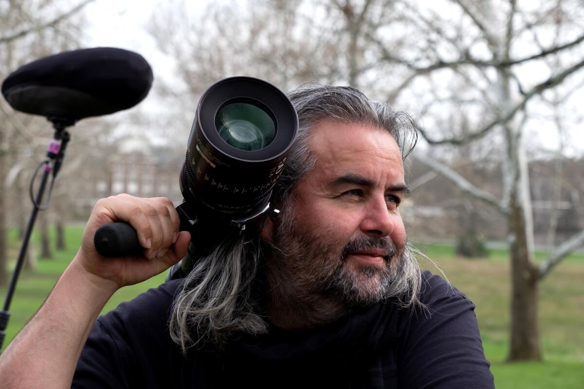 Cinematographer Hoyte van Hoytema hoists a camera lens on his shoulder on the set of "Oppenheimer."